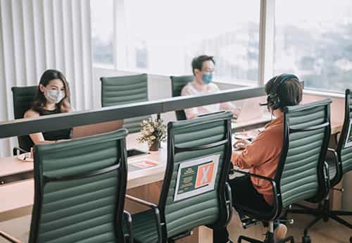 colleagues wear masks and sit at a conference table
